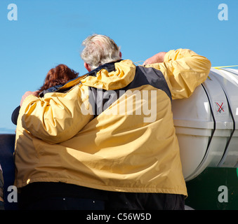 Un homme une femme de l'abris à l'aide du vent son manteau tandis qu'ils regardent fixement la mer depuis le pont d'un navire Banque D'Images