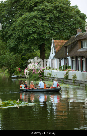 Les Pays-Bas, 's-Graveland. L'homme et des enfants en bateau à rames en face de l'ancienne ferme. Banque D'Images