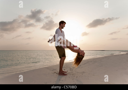 Couple sur la plage au coucher du soleil Banque D'Images