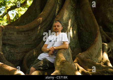 Homme parmi les racines des arbres gommeux géant dans la région de Jardim Antonio Borges, Ponta Delgada, île de São Miguel, aux Açores. Banque D'Images