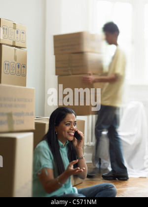 Woman on phone et unpacking boxes Banque D'Images