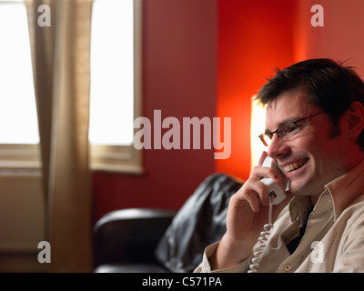 Man talking on phone in living room Banque D'Images