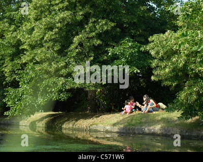 Family sitting on riverbank ensemble Banque D'Images