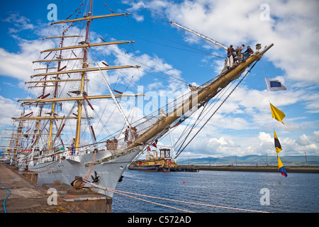 Les hommes debout de la beaupré du Dar Mlodziezy, travaillant sur le gréement d'un foc voile. Greenock, Scotland, UK Banque D'Images