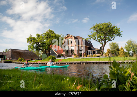 Les Pays-Bas, Giethoorn, Village avec presque seulement d'eau. Les touristes appréciant en kayak. Banque D'Images
