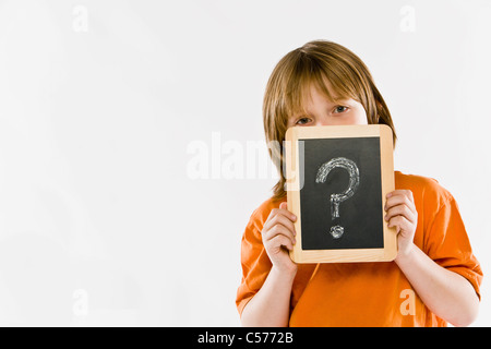 Boy holding question mark on chalkboard Banque D'Images