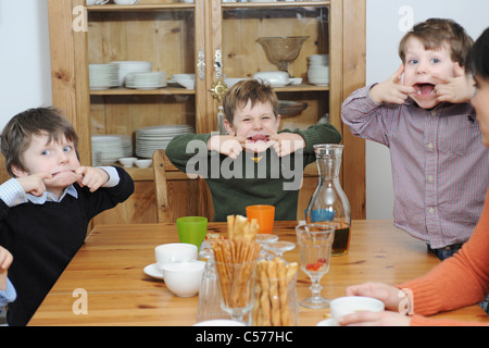 Les garçons faisant des grimaces à table Banque D'Images