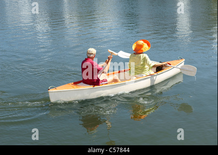 Vieux couple rowing canoe on lake Banque D'Images