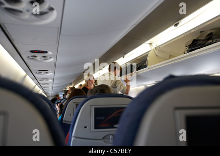 Passagers à bord d'Air Canada à bord d'un Embraer EMB190 avion de passagers en attente sur man putting assurance dans compartiment au Banque D'Images