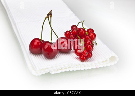 Cerises et groseilles sur un tapis blanc Banque D'Images