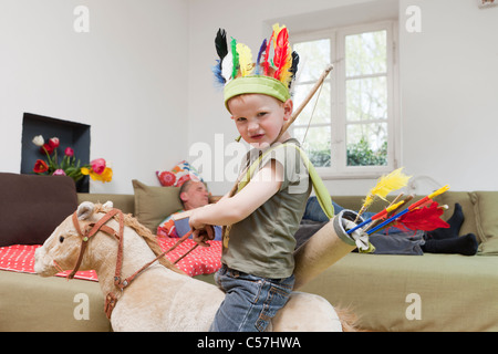 Boy in war bonnet jouant avec des jouets Banque D'Images