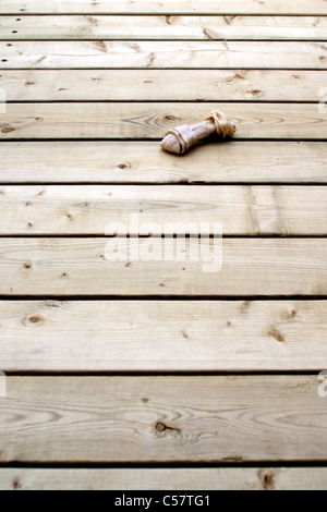 Un chien jouet à mâcher des os en cuir brut se trouve sur les planches de bois. Banque D'Images