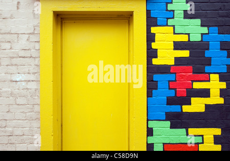 Porte jaune avec motif coloré mur de brique Banque D'Images