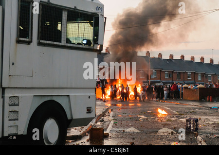 Canon à eau de la police disperse des manifestants qui ont mis le feu à une voiture volée Banque D'Images