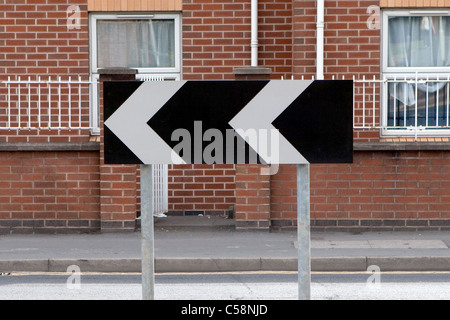 UK Chevron street sign, indiquant une prochaine forte / virage serré de la route. Le noir et blanc Banque D'Images