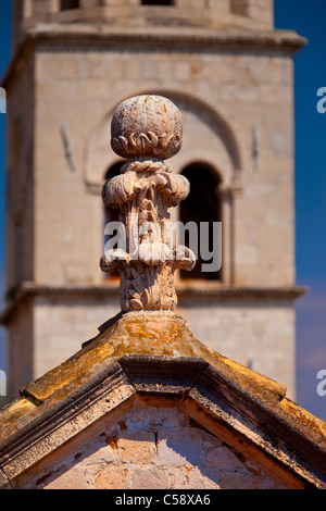 Fleuron en pierre sculptée sur toit avec clocher de l'église au-delà dans le vieux Dubrovnik, Dalmatie Croatie Banque D'Images