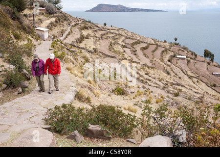 Un couple marche jusqu'à une colline lors d'une randonnée autour de la chemins et sentiers sur l'île de Taquile sur le lac Titicaca au Pérou Banque D'Images