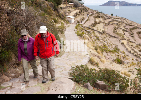 Un couple marche jusqu'à une colline lors d'une randonnée autour de la chemins et sentiers sur l'île de Taquile sur le lac Titicaca au Pérou Banque D'Images