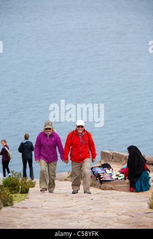 Un couple marche jusqu'à une colline lors d'une randonnée autour de la chemins et sentiers sur l'île de Taquile sur le lac Titicaca au Pérou Banque D'Images