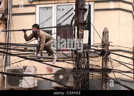 Réparateur sur lignes électriques à l'intersection de Bat Dan St et St peut accrocher vieux quartier de Hanoi, Vietnam Banque D'Images