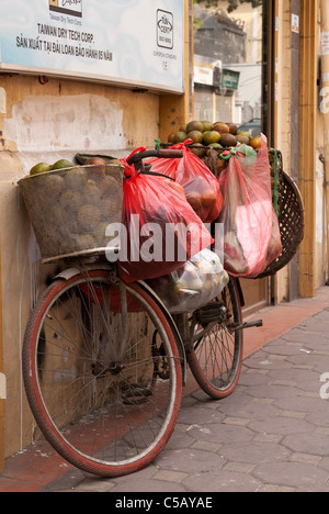 Sacs d'oranges sur un vélo appuyé contre un mur à Hang Trong St, vieux quartier de Hanoi, Vietnam Banque D'Images