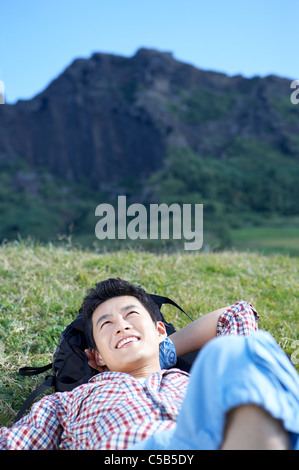 Homme étendu sur l'herbe par mountain Banque D'Images