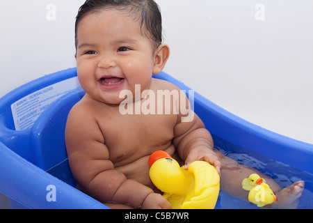 Rires de bébé jouer avec les canards en caoutchouc dans la baignoire Banque D'Images
