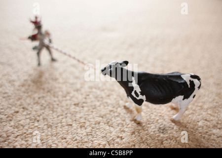 Vache jouet et figure sur la moquette Banque D'Images