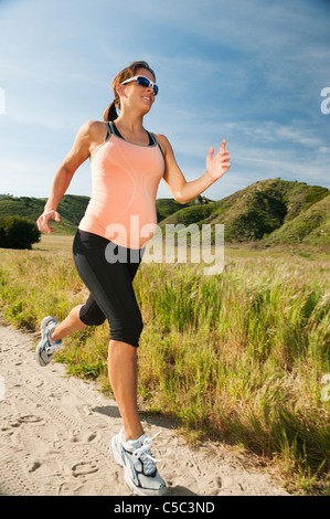 Pregnant Hispanic woman running in remote area Banque D'Images