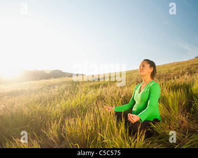 Pregnant Hispanic woman practicing yoga in field Banque D'Images