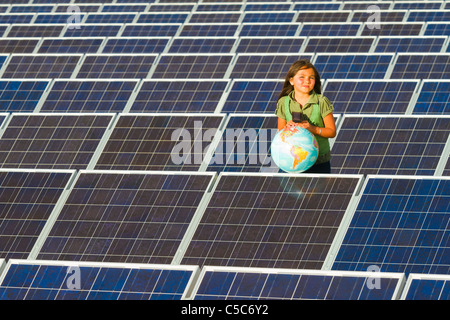 Native American Girl standing près de panneaux solaires holding globe Banque D'Images