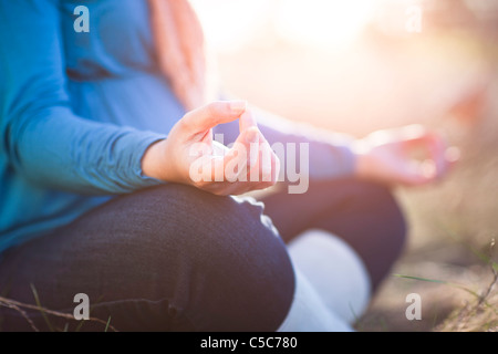 Pregnant woman practicing yoga in field Banque D'Images