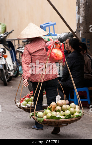 Colporteur portant des paniers de fruits, bat Dan St, vieux quartier de Hanoi, Vietnam Banque D'Images