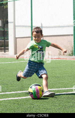 Petit garçon,jouer au football,botter un ballon Banque D'Images