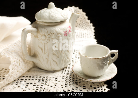 Un ancien enfant's tea set s'affiche sur un morceau de vieilles dentelles Banque D'Images