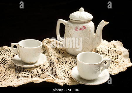 Un ancien enfant's tea set s'affiche sur un morceau de vieilles dentelles Banque D'Images