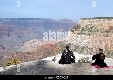 Une paire de touristes s'arrêter pour prendre des photos et de vous détendre à l'Trailview donnent sur le long de la rive sud du Grand Canyon National Park. Banque D'Images