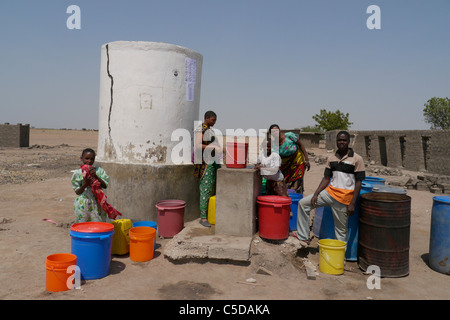 Tanzanie Village d'Mwamalasa, Shinyanga. La collecte de l'eau d'un réservoir de stockage. L'eau est pompée par les éoliennes dans le réservoir. Banque D'Images