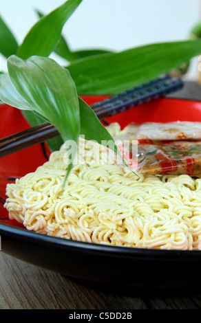 Instant fast food nouilles asiatiques avec des baguettes dans une tasse rouge Banque D'Images