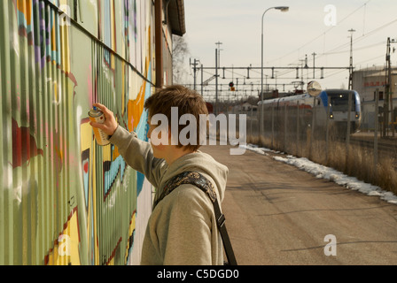 Vue latérale d'un adolescent sur le mur de graffiti de pulvérisation