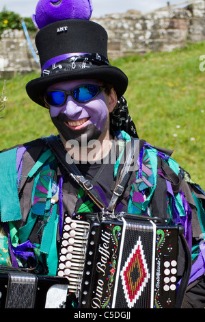 Frontière d'Exmoor Danseurs Morris mixte, black-faced, portant longue de vieux chiffons déchirés, des vêtements faits à partir de la grande vis du matériau bleu et blanc, vêtements Banque D'Images