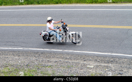 Une femme équitation une Harley Davidson moto moto sur une route de montagne. Banque D'Images