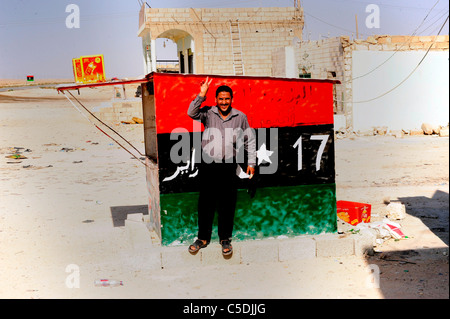 Un homme se tient devant le nouveau drapeau libyen peint sur un mur à côté de Benghazi Banque D'Images