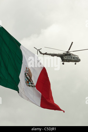 Un hélicoptère militaire Marine mexicaine patrouillant la rivière Rio Grande comme elle va au-delà d'un grand drapeau mexicain à la frontière américaine Banque D'Images