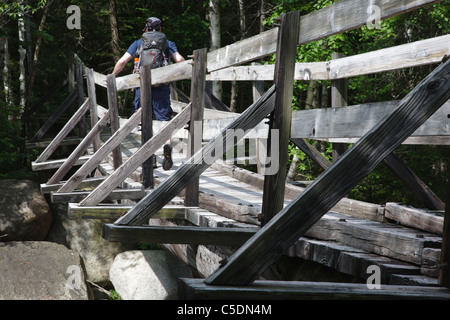 Pemigewasset Wilderness - Un randonneur sur la passerelle en bois qui traverse le bras est de la rivière Pemigewasset dans le New Hampshire. Banque D'Images