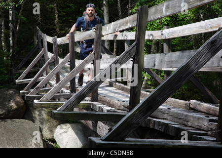 Pemigewasset Wilderness - Un randonneur sur la passerelle en bois qui traverse le bras est de la rivière Pemigewasset dans le New Hampshire. Banque D'Images