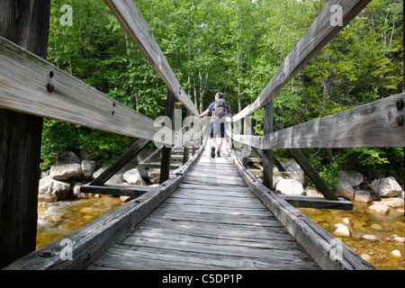 Pemigewasset Wilderness - Un randonneur sur la passerelle en bois qui traverse le bras est de la rivière Pemigewasset dans le New Hampshire. Banque D'Images