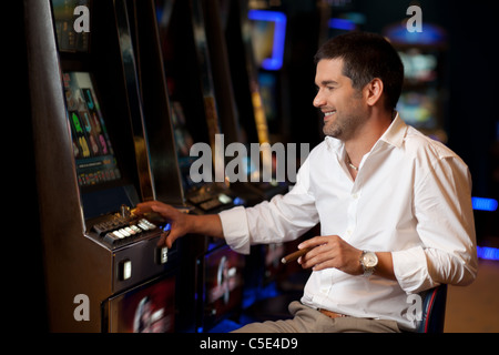 Smiling handsome man l'espoir de gagner à la machine à sous Banque D'Images