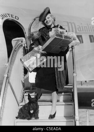 Femme avec des dons descendre les escaliers de l'avion Banque D'Images