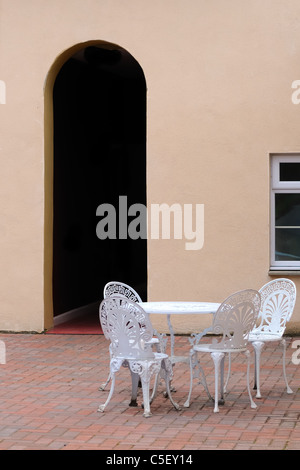 Table et chaises dans la cour avec porte voûtée Banque D'Images